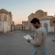 فردی در تقاطع خلوت شهری در حال مکث و بی موضعی در تصمیم‌گیری؛ تصویر مفهومی تعلیق ارادی تصمیم و زندگی معلق